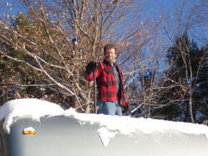 Trey is shoveling snow off the roof of the RV.